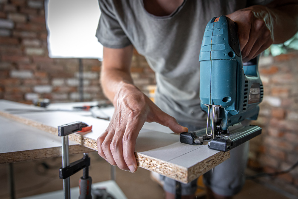 male-carpenter-cuts-wood-with-electric-jigsaw-working-with-tree (1)